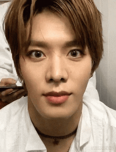 A Close Up Of A Young Man 'S Face Wearing A Choker Necklace And A White Shirt . GIF