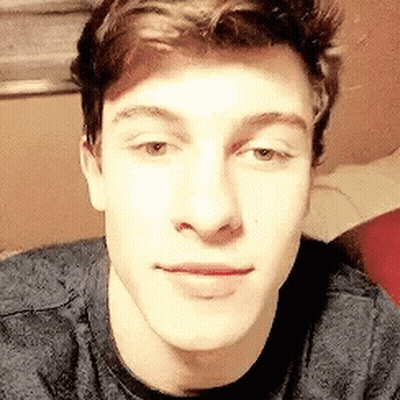 A Close Up Of A Young Man 'S Face Wearing A Grey Shirt . GIF
