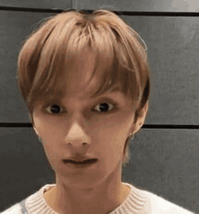 A Close Up Of A Young Man 'S Face Wearing A White Sweater And Making A Funny Face . GIF