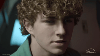 A Close Up Of A Young Man 'S Face With A Disney + Logo In The Background GIF