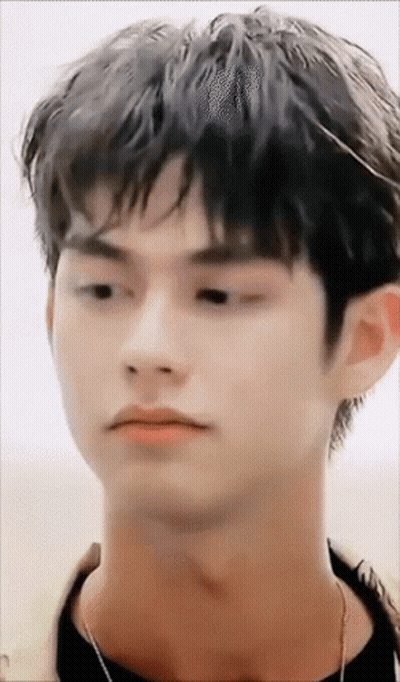 A Close Up Of A Young Man 'S Face With A Necklace Around His Neck Looking At The Camera . GIF