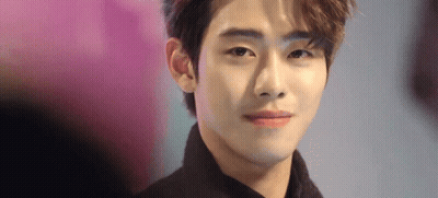 A Close Up Of A Young Man 'S Face With A Pink Background Looking At The Camera . GIF