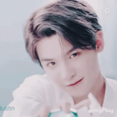 A Close Up Of A Young Man 'S Face With A Smile On His Face And A White Shirt On . GIF