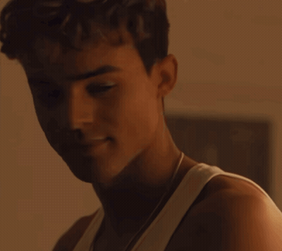 A Close Up Of A Young Man 'S Face With A White Tank Top On GIF