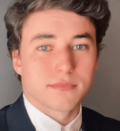 A Close Up Of A Young Man 'S Face With Blue Eyes Wearing A Suit And White Shirt . GIF