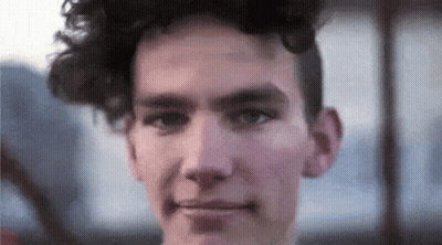 a close up of a young man 's face with curly hair