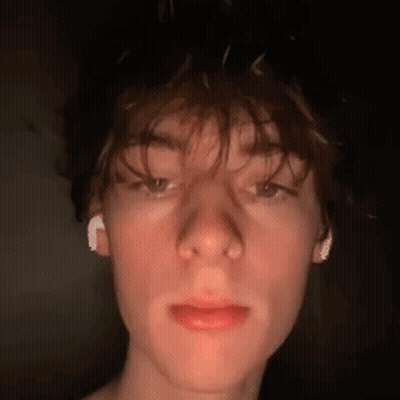 A Close Up Of A Young Man 'S Face With Ear Buds In His Ears . GIF