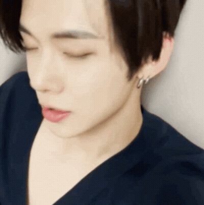 A Close Up Of A Young Man 'S Face With His Eyes Closed And Earrings . GIF