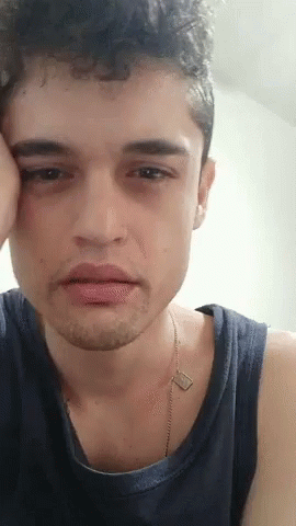 A Close Up Of A Young Man 'S Face With His Hand On His Face . GIF