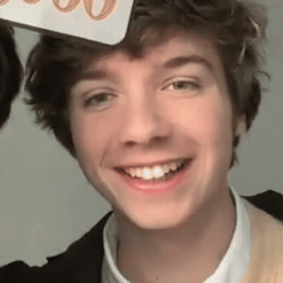 A Close Up Of A Young Man Smiling While Wearing A Hat On His Head . GIF
