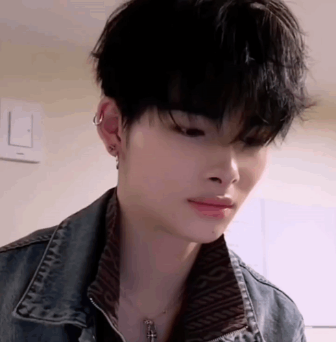 A Close Up Of A Young Man Wearing A Denim Jacket And A Necklace With A Cross . GIF