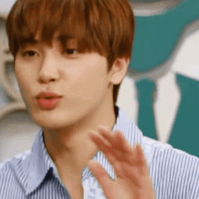 A Close Up Of A Young Man Wearing A Striped Shirt And Tie Waving His Hand . GIF