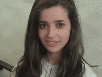A Close Up Of A Young Woman 'S Face With Long Hair . GIF