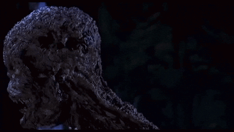 A Close Up Of A Zombie With Its Arms Outstretched In A Dark Room GIF