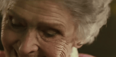 A Close Up Of An Elderly Woman 'S Face With Wrinkles And A Pink Shirt . GIF