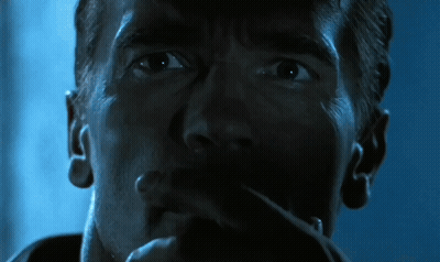 A Close Up Of Arnold Schwarzenegger 'S Face In A Dark Room GIF