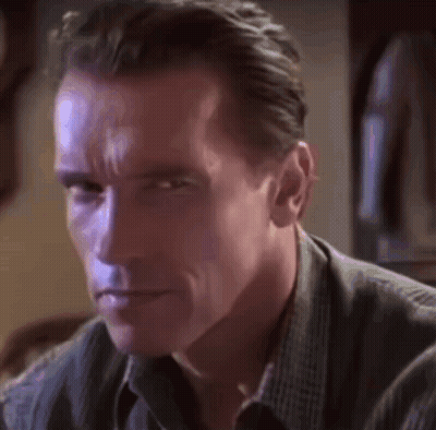 A Close Up Of Arnold Schwarzenegger 'S Face In A Dark Room GIF