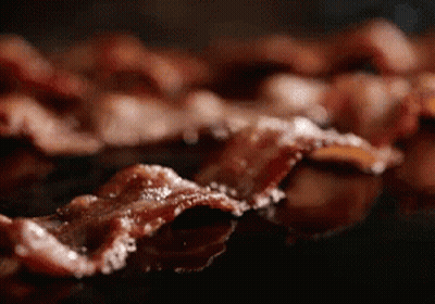 A Close Up Of Bacon Being Cooked In A Pan GIF
