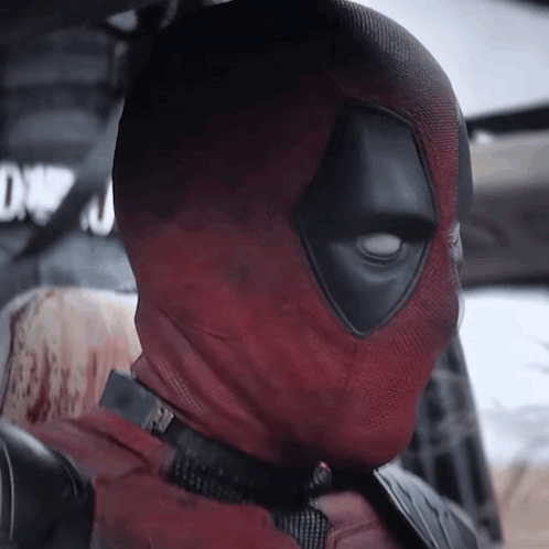 A Close Up Of Deadpool 'S Face With A Sign In The Background That Says Dwn GIF