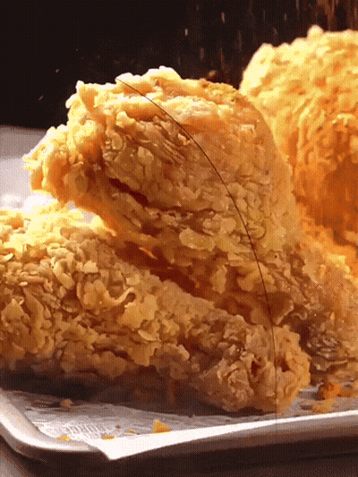 A Close Up Of Fried Chicken On A Tray With A Piece Missing GIF