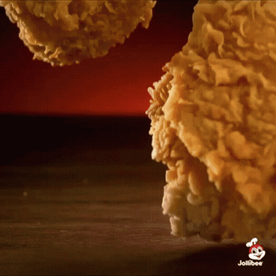 A Close Up Of Fried Chicken On A Wooden Table With A Jollibee Logo In The Corner . GIF