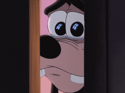 A Close Up Of Goofy 'S Face Peeking Out From Behind A Door GIF