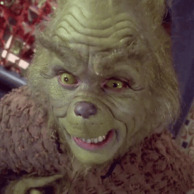 A Close Up Of Grinch 'S Face With Yellow Eyes And A Pink Teeth GIF