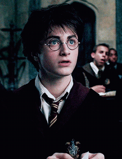 A Close Up Of Harry Potter Wearing Glasses And A Slytherin Crest GIF