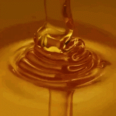 A Close Up Of Honey Pouring Into A Bowl Of Liquid . GIF
