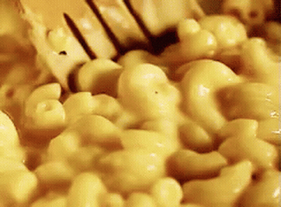 A Close Up Of Macaroni And Cheese Being Stirred With A Fork GIF
