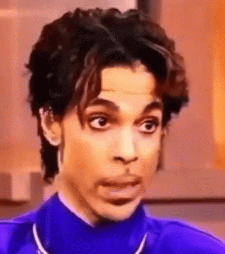 A Close Up Of Prince Making A Funny Face While Wearing A Purple Jacket . GIF