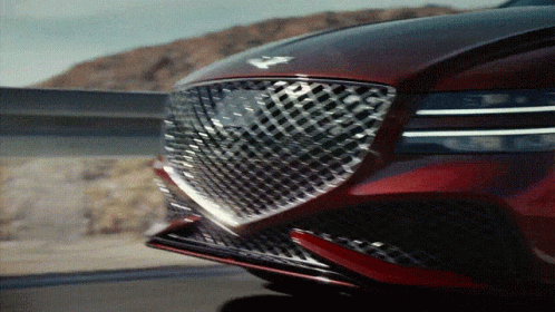 A Close Up Of The Front Of A Red Car With A Checkered Grill GIF