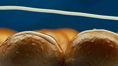 A Close Up Of Two Glazed Doughnuts On A Blue Surface GIF