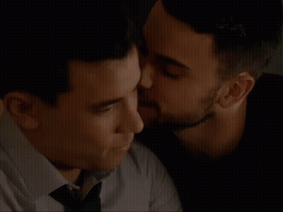 A Close Up Of Two Men Kissing Each Other On The Cheek . GIF