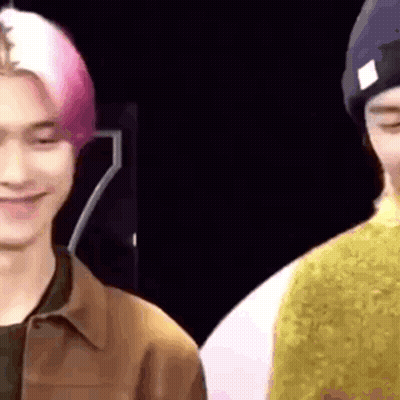 A Close Up Of Two Men Standing Next To Each Other And Smiling . GIF
