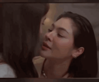 A Close Up Of Two Women Kissing Each Other On The Forehead . GIF
