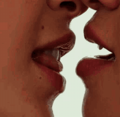 A Close Up Of Two Women Kissing Each Other On The Lips . GIF