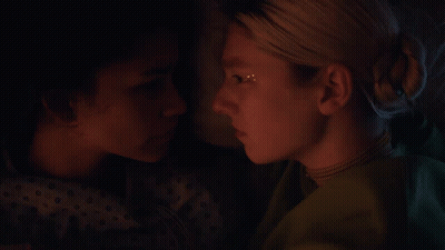 A Close Up Of Two Women Looking At Each Other In A Dark Room GIF