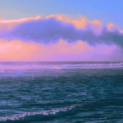 A Cloudy Sky Over The Ocean With Waves Crashing On The Shore GIF