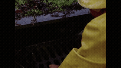 A Clown In A Yellow Raincoat Is Peeking Out Of A Drain And Says Halo GIF
