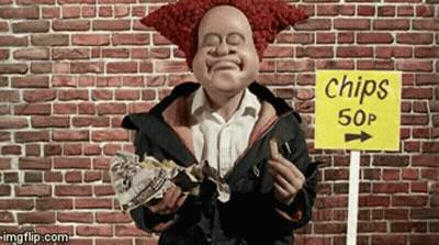 A Clown Is Eating Chips In Front Of A Brick Wall GIF
