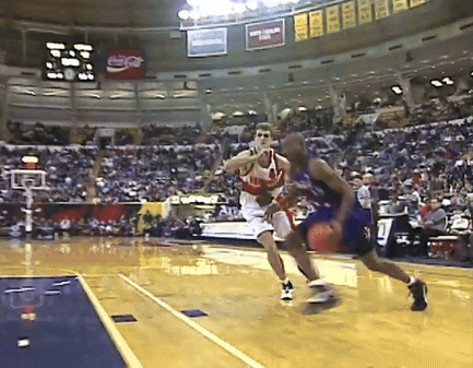 A Coca Cola Sign Hangs From The Ceiling Of A Basketball Court GIF