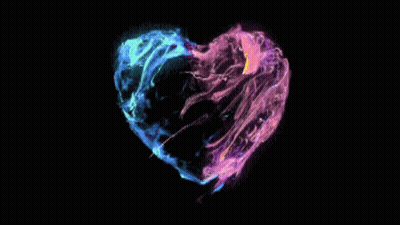 A Colorful Heart Shaped Object Is Floating In The Dark GIF