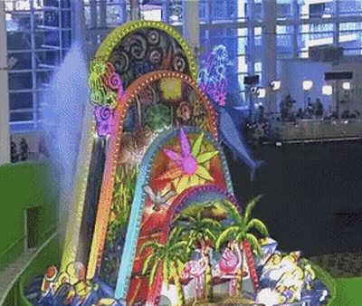 A Colorful Sculpture With A Dolphin In The Background Is Displayed In A Building GIF