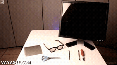 A Computer Monitor Sits On Top Of A White Table With Various Tools And Glasses On It GIF