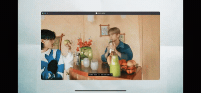 A Computer Screen Shows Two People Sitting At A Table Drinking From Bottles . GIF
