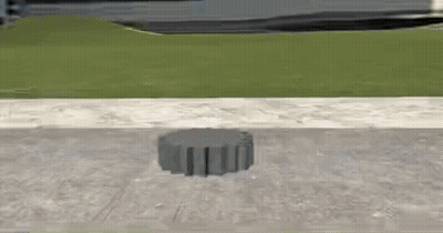 A Concrete Block Is Sitting On The Sidewalk Next To A Grassy Hill . GIF