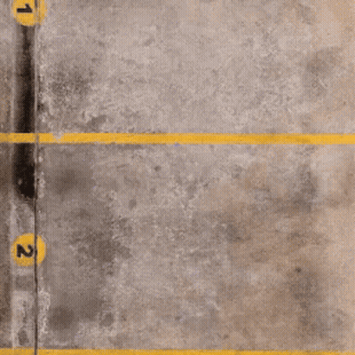 A Concrete Parking Lot With Yellow Lines And Numbers 1 And 2 GIF