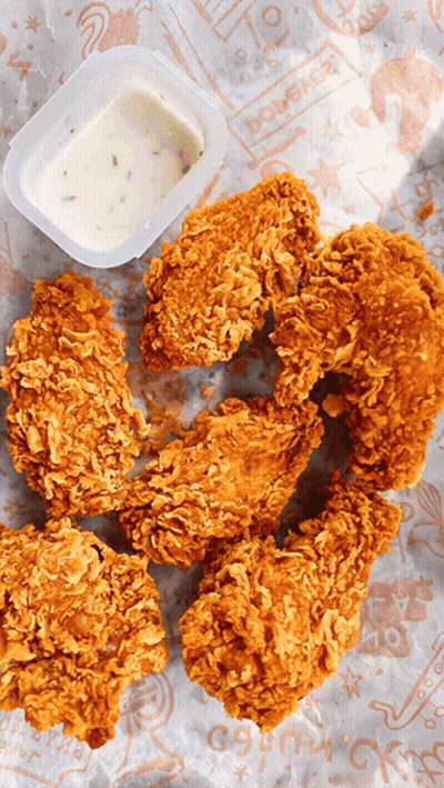 A Container Of Dipping Sauce Sits Next To A Pile Of Fried Chicken Wings GIF