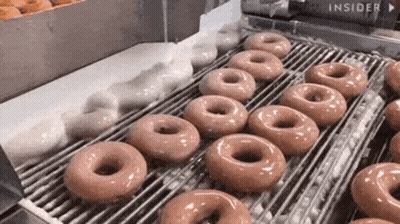A Conveyor Belt Filled With Doughnuts Being Made In A Doughnut Shop . GIF